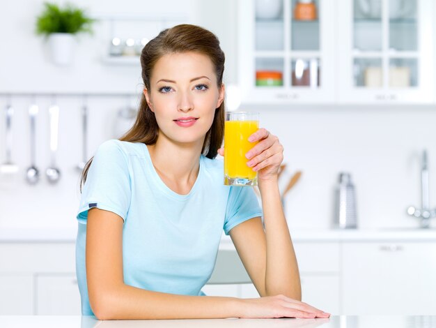 Hermosa joven sostenga un vaso de jugo de naranja natural