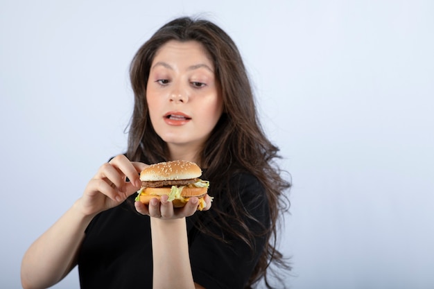 Hermosa joven sosteniendo una deliciosa hamburguesa de ternera.