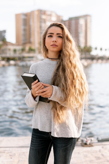 Hermosa joven sosteniendo un libro afuera