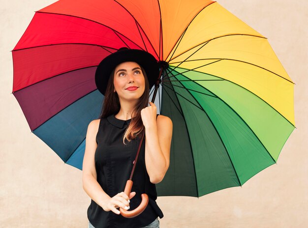 Hermosa joven sosteniendo un paraguas de arco iris