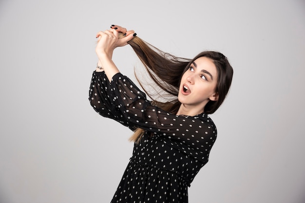 Foto gratuita una hermosa joven sosteniendo su cabello sano y brillante.