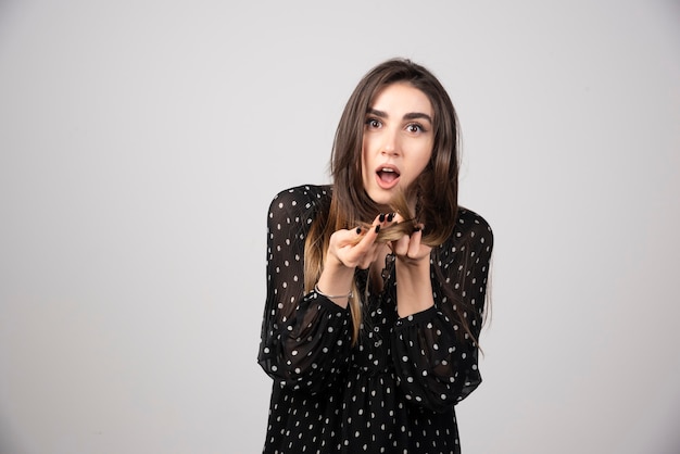 Foto gratuita una hermosa joven sosteniendo su cabello sano y brillante.