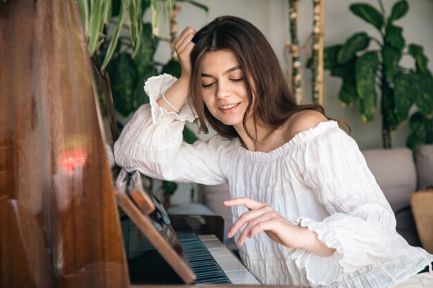 Foto gratuita una hermosa joven toca el viejo piano de madera.