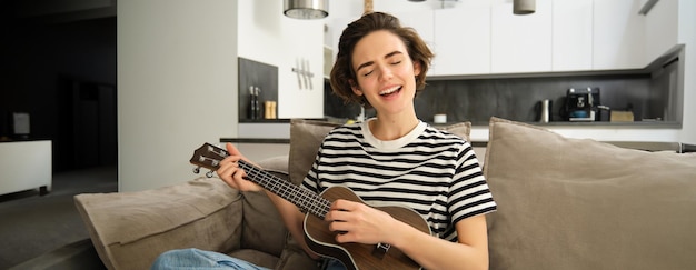 Foto gratuita hermosa joven tocando el ukelele cantando y disfrutando de su instrumento musical pasando el tiempo