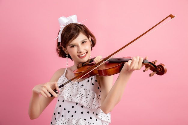 Hermosa joven tocando el violín sobre rosa