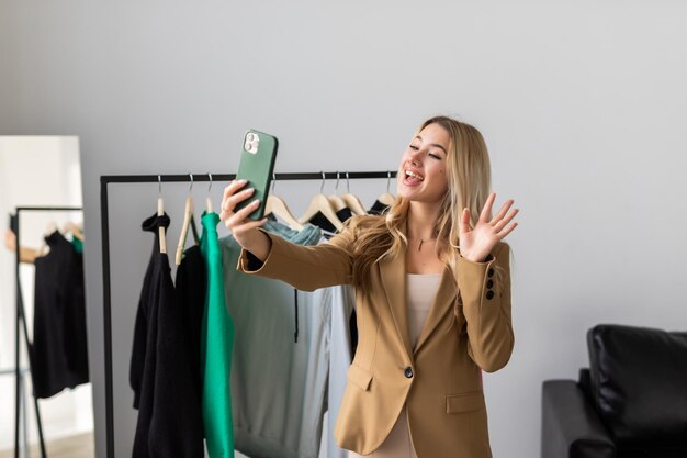 Hermosa joven tomando selfie en la tienda con ropa de moda