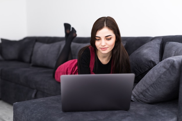 Hermosa joven trabajando en la computadora portátil en casa