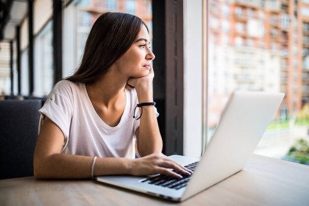 Hermosa joven usando laptop en café