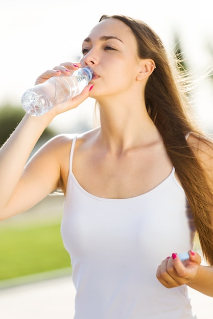 Foto gratuita hermosa joven woma agua potable en la calle.