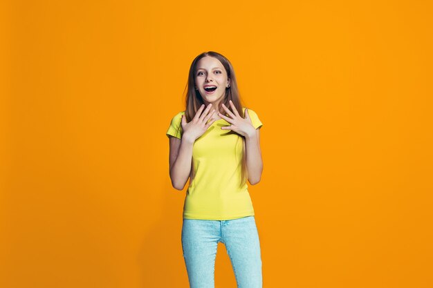 Hermosa jovencita mirando sorprendido aislado en naranja