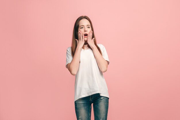 Hermosa jovencita mirando sorprendido aislado en la pared rosa