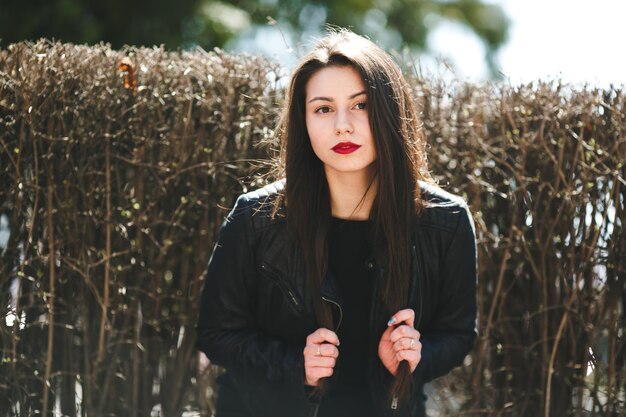 Hermosa jovencita posando en una chaqueta de cuero negro en el parque