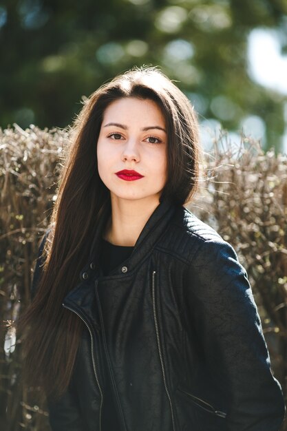 Hermosa jovencita posando en una chaqueta de cuero negro en el parque