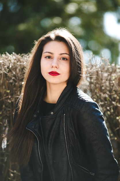 Hermosa jovencita posando en una chaqueta de cuero negro en el parque