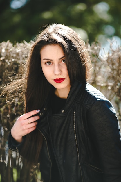 Hermosa jovencita posando en una chaqueta de cuero negro en el parque