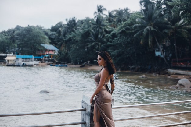 Hermosa jovencita posando en la playa, el océano, las olas, el sol brillante y la piel bronceada.