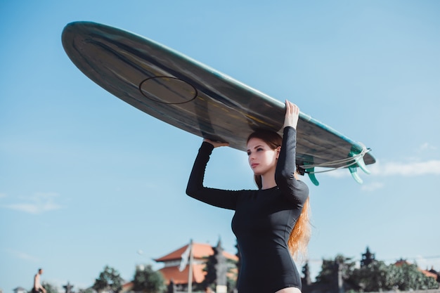 Hermosa jovencita posando en la playa, el océano, las olas, el sol brillante y la piel bronceada.