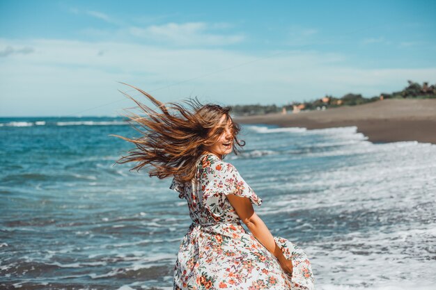 Hermosa jovencita posando en la playa, el océano, las olas, el sol brillante y la piel bronceada.