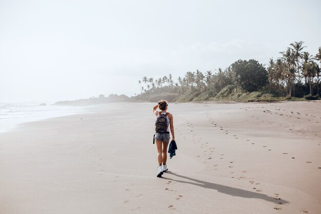 Hermosa jovencita posando en la playa, el océano, las olas, el sol brillante y la piel bronceada.