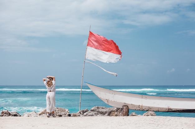 Hermosa jovencita posando en la playa, el océano, las olas, el sol brillante y la piel bronceada.