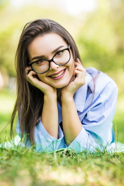 Hermosa jovencita soñadora recostada sobre la hierba en el parque