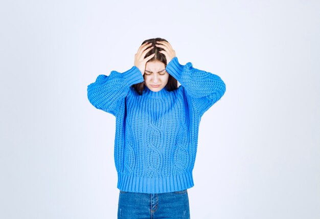 Hermosa jovencita vestida con suéter azul cogidos de la mano en la cabeza.