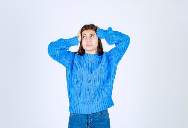 Hermosa jovencita vestida con suéter azul cogidos de la mano en la cabeza.