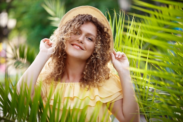 Hermosa jovencita en vestido amarillo posando en el parque de la ciudad.