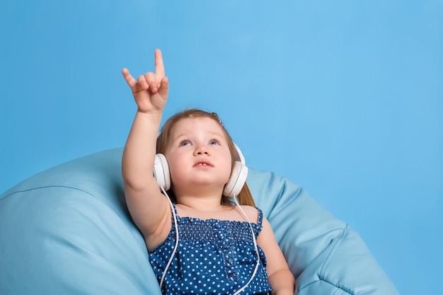 Foto gratuita hermosa linda niña feliz con auriculares en un fondo azul en el estudio