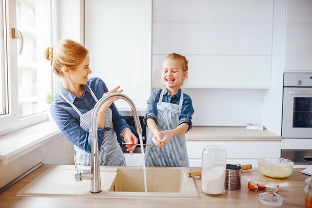 hermosa madre con una camisa azul y un delantal está preparando la cena en casa en la cocina