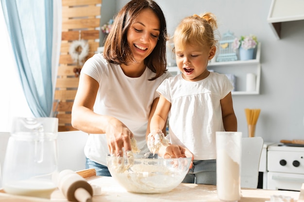 Hermosa madre y linda chica preparando masa