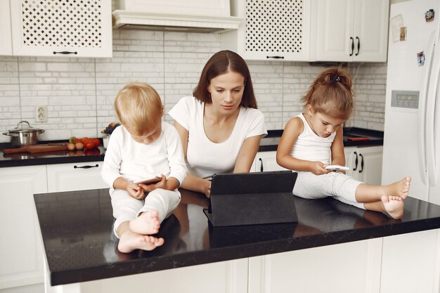 Hermosa madre con lindos hijos en casa en una cocina