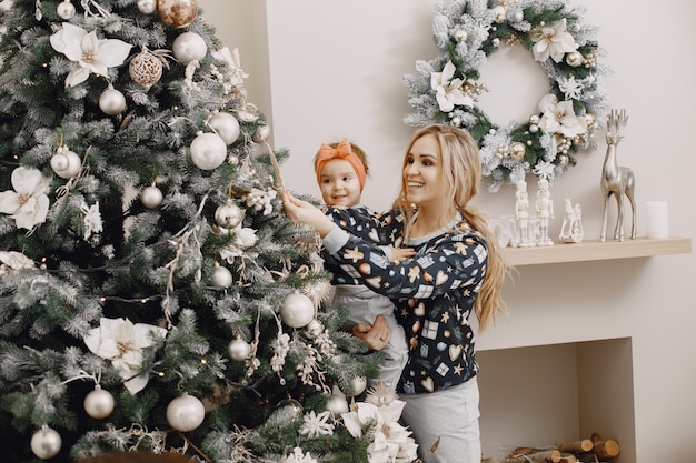 Hermosa madre con niño. Familia en ambiente navideño. Personas vestidas con árbol de Navidad.