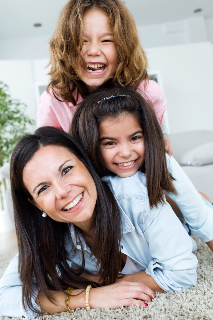 Foto gratuito hermosa madre con sus hijas mirando la cámara en casa.