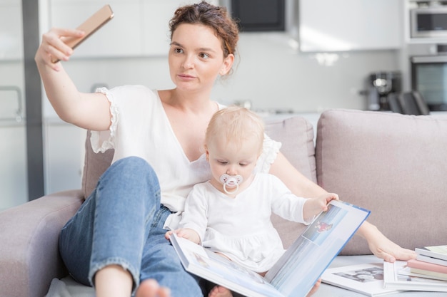 Foto gratuita hermosa madre tomando una selfie con bebé