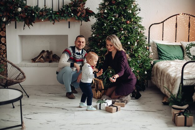 Hermosa mamá y papá decoran un árbol de Navidad con su amado hijo en casa
