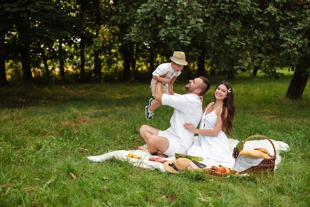 Hermosa mamá, papá y su lindo niño se divierten juntos y sonríen afuera