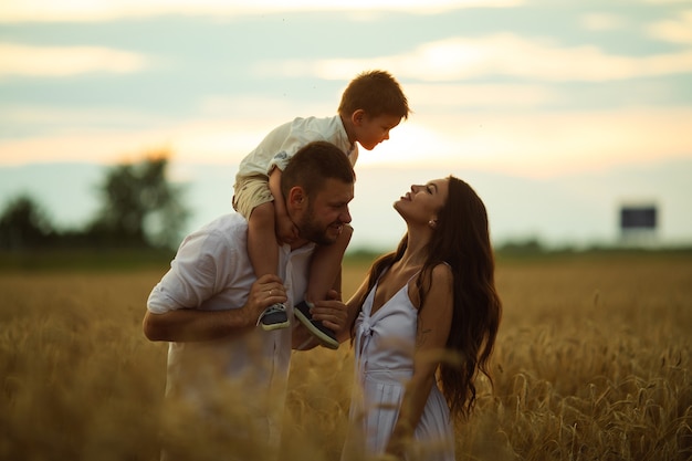 Hermosa mamá, papá y su lindo niño se divierten juntos y sonríen afuera