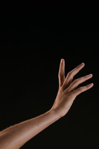 Hermosa mano con dedos extendidos sobre fondo negro
