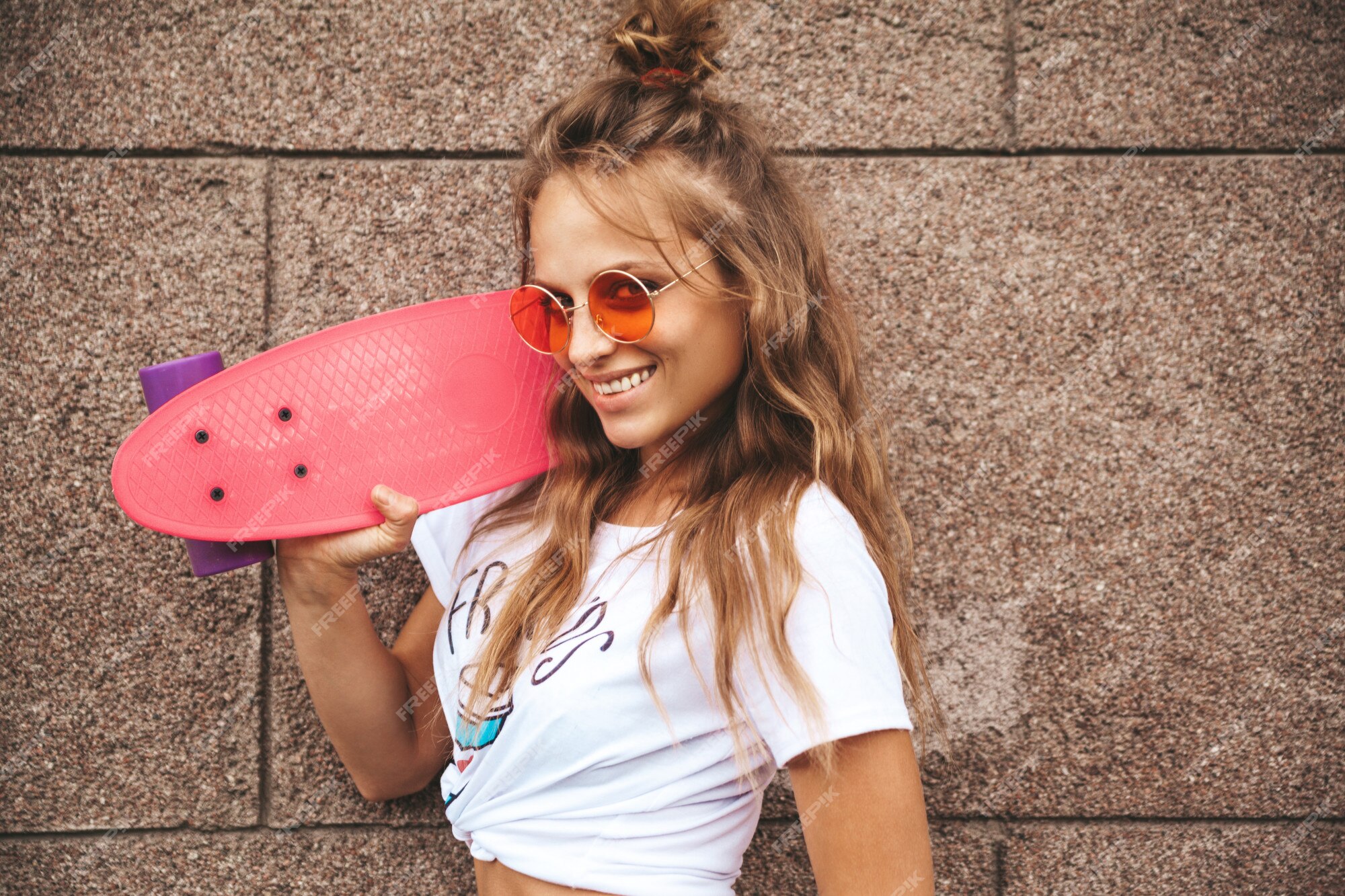 Hermosa modelo de adolescente rubia linda sin maquillaje en ropa blanca  hipster de verano con patineta rosa centavo posando junto a la pared en la  calle | Foto Gratis