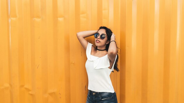 Hermosa modelo brasileña posando contra la pared naranja