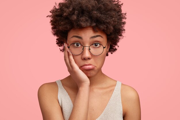 Hermosa modelo femenina desconcertada mantiene la mano en la mejilla