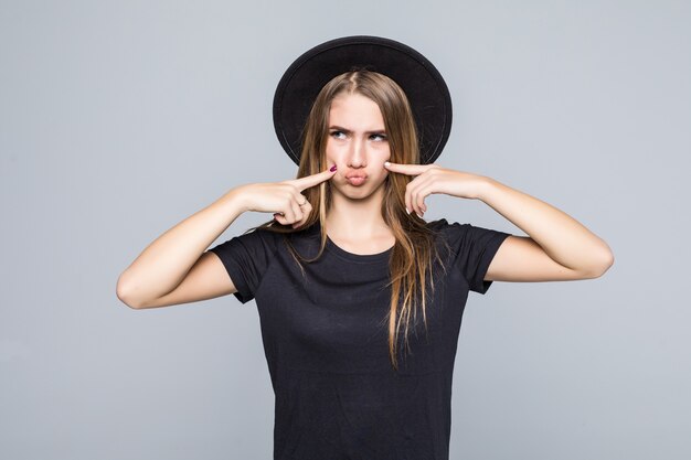 Hermosa modelo de mujer joven muestra emociones vestidas con ropa oscura aislada sobre fondo gris