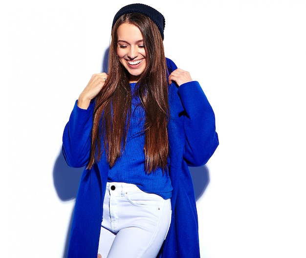 Hermosa modelo de mujer morena hipster sonriente en elegante abrigo azul aislado en blanco