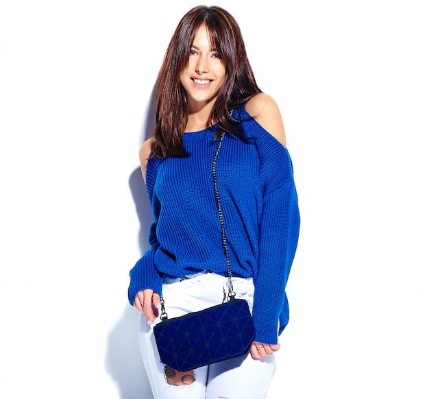 Hermosa modelo de mujer morena hipster sonriente en suéter de verano elegante casual y bolso azul aislado sobre fondo blanco