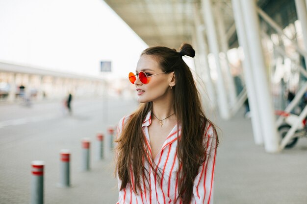 Hermosa modelo con posturas de pelo largo en gafas de sol rojas