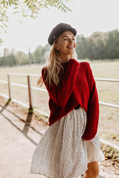 Hermosa modelo sonriendo con placer en un agradable fondo soleado Hermosa chica rubia sintiéndose alegre en el parque de otoño