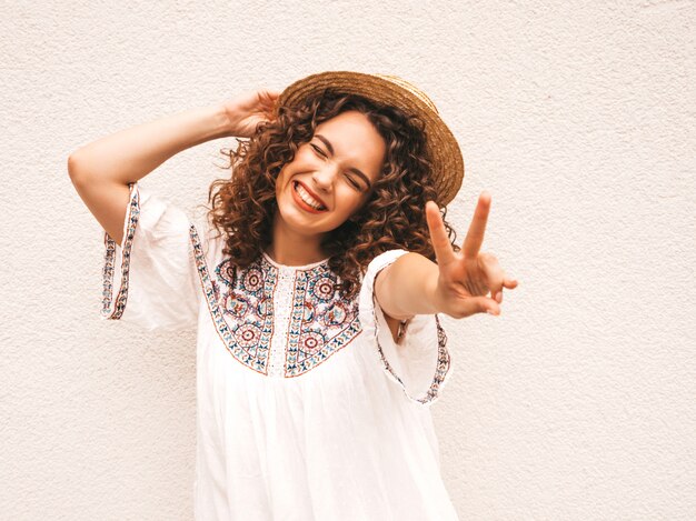 Hermosa modelo sonriente con peinado afro rizos vestido con vestido blanco hipster de verano.