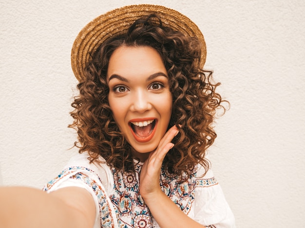 Hermosa modelo sonriente con peinado afro rizos vestido con vestido blanco hipster de verano.