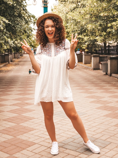 Foto gratuita hermosa modelo sonriente con peinado afro rizos vestido con vestido blanco hipster de verano.